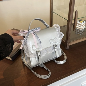 Silver Lolita style backpack with lace trim and pink bows on a wooden display