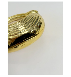 Detail of gold metallic clutch bag with pleated texture and round ring handle