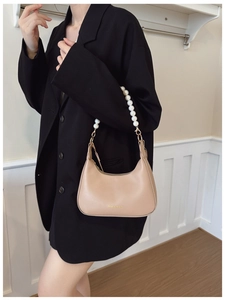Beige hobo shoulder bag with large faux pearl strap and gold zipper details on a model