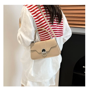 Detail of a beige leather shoulder bag with a silver metal clasp worn by a model