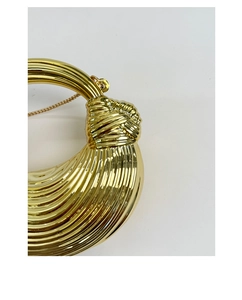 Close-up of golden metallic knot handle with textured vertical stripes on chic handbag