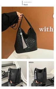 Detail of black leather bucket bag with embossed lettering and grey tassel charm