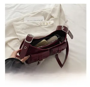 Dettaglio della borsa a spalla in pelle bordeaux con interno spazioso e due tasche frontali