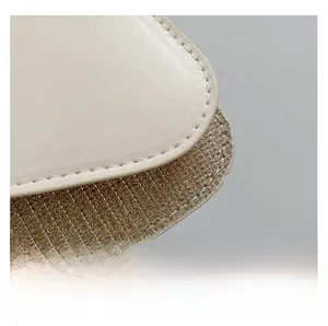 Close-up of cream leather stitching and gold sequin woven texture on square bag