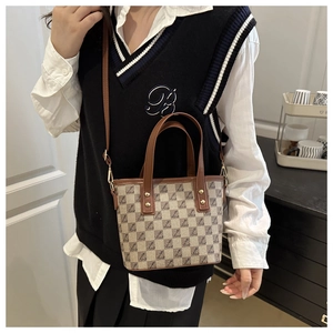 Detail of checkered bucket bag with leather handles and detachable long shoulder strap