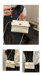 Detail of white crossbody bag with gold twist lock and geometric embossed texture