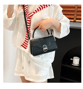 Detail of black leather crossbody bag with silver oval metal clasp and top handle
