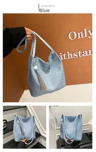 Detail of light blue tote bag with embossed letter patterns and decorative grey tassel