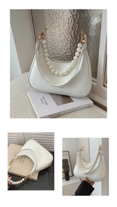 Detail view of white baguette bag featuring large pearl handle and gold metal buckles