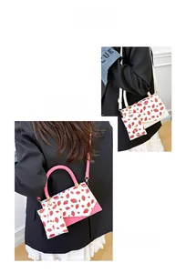 Detail of strawberry print crossbody bag with mini pouch accessory and top handle strap