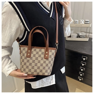 Close-up of stylish brown checkered bucket bag with vintage monogram and gold hardware