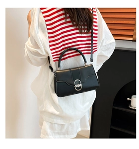 Minimalist black matte leather underarm bag with silver oval metal lock shown on a model