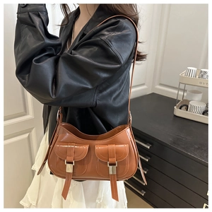 Dettaglio della borsa a spalla in pelle lucida marrone con tasche in stile retrò
