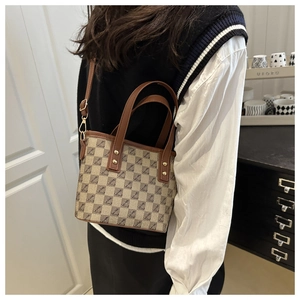 Detail of monogram canvas tote bag with brown leather handles and golden hardware