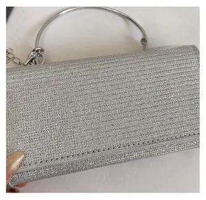 Detail of silver evening clutch with glitter texture, round metal handle and chain strap