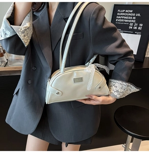 Dettaglio borsa bowling in pelle beige con nastro di pizzo e targhetta logo in metallo