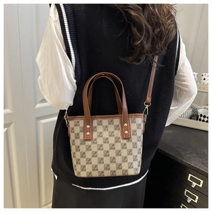 Detail of vintage plaid bucket bag with brown handles and golden rivet hardware
