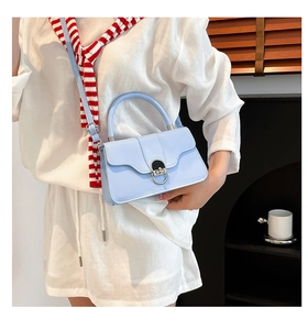 Detail of light blue crossbody bag featuring a silver oval metal twist-lock buckle
