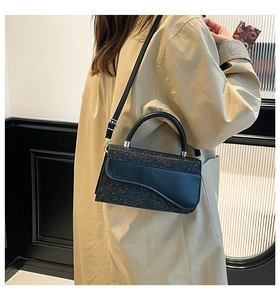 Detail of black sequined saddle bag with asymmetric flap and silver metal hardware