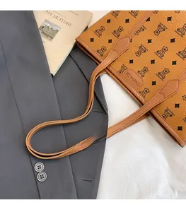 Detailed shot of brown faux leather tote featuring bear pattern and logo patch detail