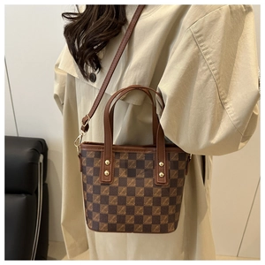 Close-up of retro checkered bucket bag with leather handles and gold hardware details