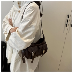 Dettaglio borsa sottobraccio in vernice marrone scuro con fibbie e due tasche anteriori