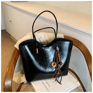 Detailed shot of black leather tote bag with vintage wood ring charm and magnetic buckle