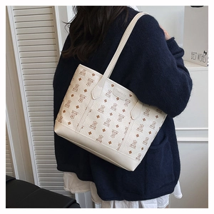 Detail of a beige tote bag with bear print and Creative Cat leather label shown on shoulder
