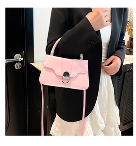 Detailed view of pink shoulder bag featuring a silver circular metal lock and smooth leather