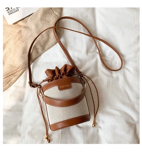 Close-up of retro bucket bag with brown faux leather trim and drawstring closure