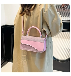 Close-up of pink sequin crossbody bag with leather flap worn with a beige trench coat