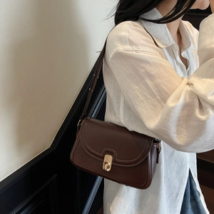 Retro chocolate brown crossbody bag with gold buckle shown on a model in white shirt