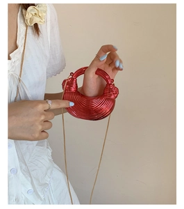 Detail of red crescent bag with pleated metallic texture and gold chain strap