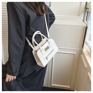 Minimalist white Boston bag with adjustable strap worn over a black coat detail