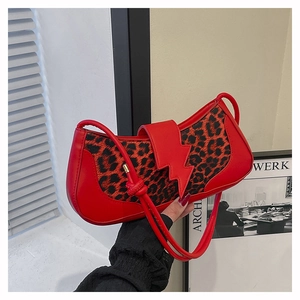 Primer plano de un bolso de hombro de retazos de leopardo rojo con diseño de rayo.