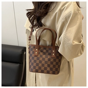 Detail of checkered bucket bag featuring golden rivets and adjustable leather strap