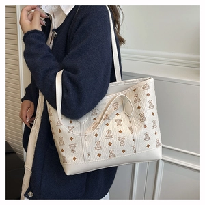 Close-up of cream white tote bag with brown bear monogram print and textured vegan leather