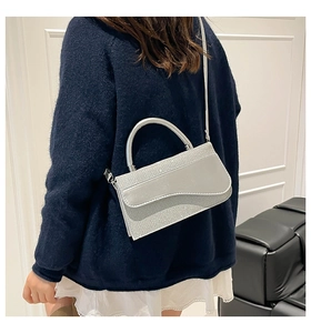 Silver glitter baguette bag with top handle and shoulder strap shown on a model