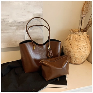 Detail of dark brown glossy leather tote bag with chocolate charm and matching pouch