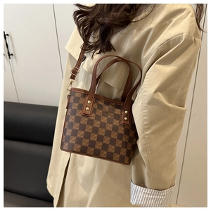 Detailed view of a brown checkered mini bucket bag with gold hardware and shoulder strap