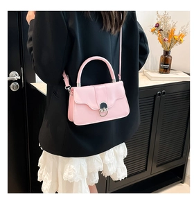 Detailed shot of pink leather handbag with black silver metal lock on a black blazer