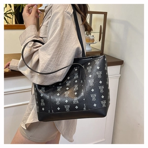 Close-up of a large black leather tote bag with bear patterns and refined lychee texture
