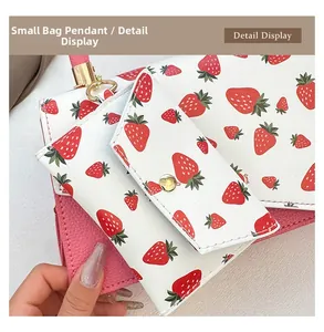 Detail view of mini strawberry print charm on pink textured leather shoulder bag