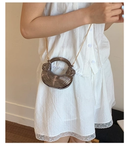 Detail of grey metallic crescent bag with rippled texture and golden chain strap