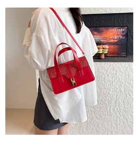 Detail of red glitter flap handbag with gold metal lock worn with a white shirt