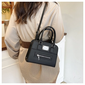 Detail view of a black Boston bag with silver hardware and adjustable strap on a model