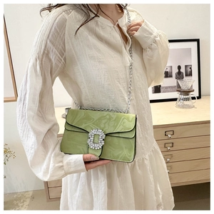 Detail shot of a light green quilted chain bag featuring a luxury diamond square buckle