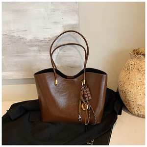 Detail of glossy brown tote bag featuring unique chocolate pendant and vintage leather texture