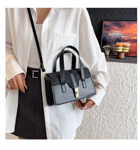 Detail of black crossbody bag featuring matte leather, sequin flap and gold twist lock