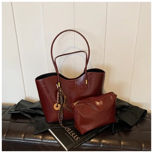 Detail of wine red glossy leather tote bag set with decorative braided charm on leather seat